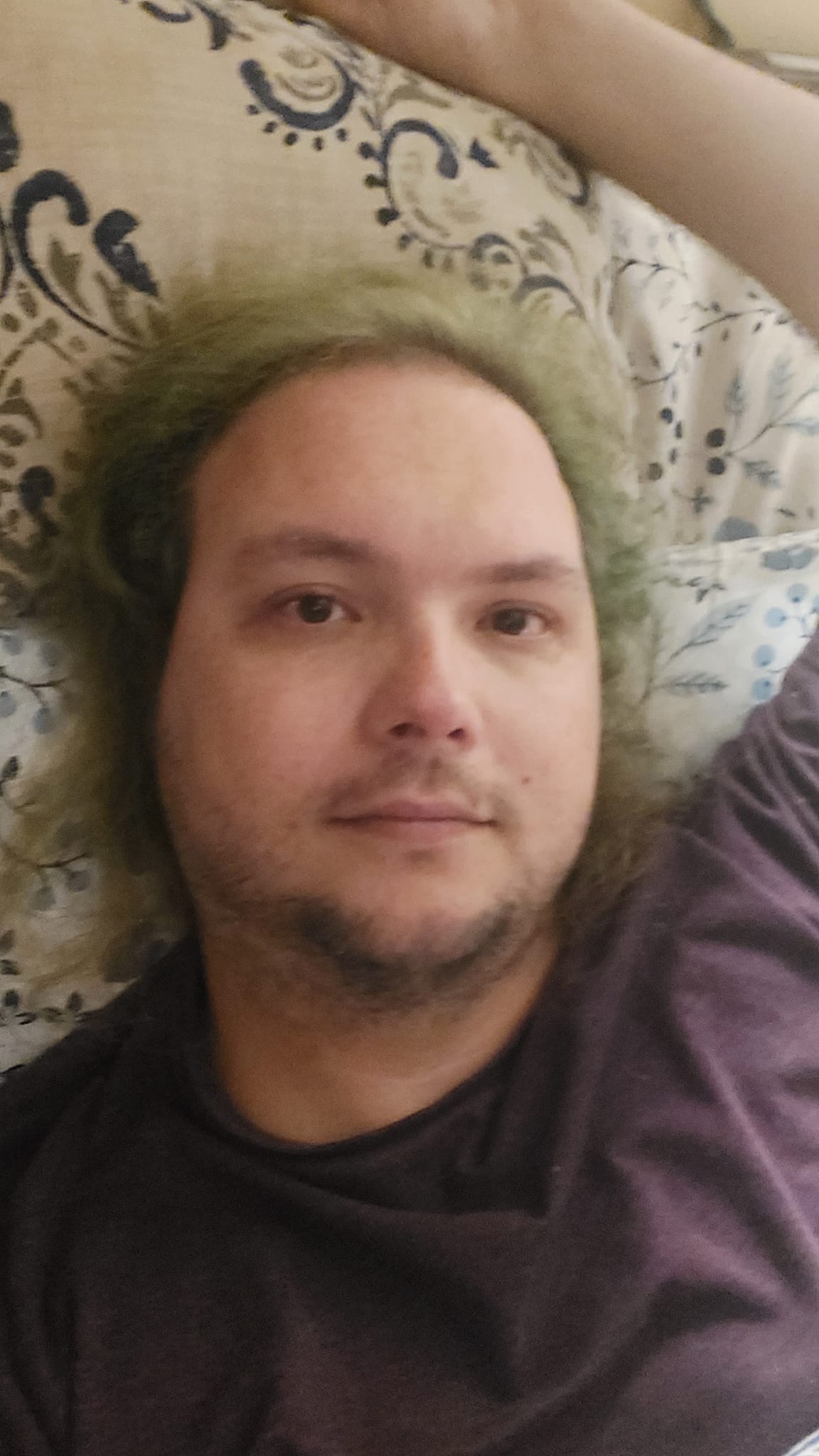 A man with long green hair wears pajamas while laying in bed, photo 2